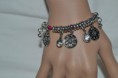 Bracelet pampilles et perles métal ciselé et argenté et strass de verre sur cordon élastique fuschia.